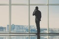 Back view of young businessman is looking out of a panoramic window and talking by phone Royalty Free Stock Photo