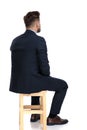 Back view of young businessman sitting on wooden chair