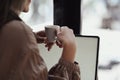 Back view of businesswoman sitting in front of laptop computer and drinking coffee. Royalty Free Stock Photo