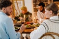 Back view of young couple having traditional Christmas dinner with friends