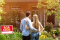 Back view of young couple standing in front yard of their new house, outside Royalty Free Stock Photo
