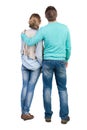 Back view of young embracing couple (man and woman) who hugs and looks