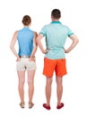 Back view of young embracing couple in shorts hug and look. Royalty Free Stock Photo