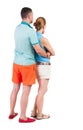 Back view of young embracing couple in shorts hug and look. Royalty Free Stock Photo