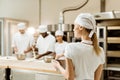 back view of young female baker at workplace with blurred colleagues working Royalty Free Stock Photo
