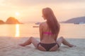 Back view of young female with long brown hair sitting on beach legs spread far apart in black bikini panties admiring Royalty Free Stock Photo