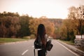 Back view of young female traveler wearing leather jacket and backpack standing on the road looking away Royalty Free Stock Photo