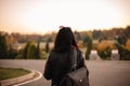 Back view of young female traveler wearing leather jacket and sunglasses standing on the road Royalty Free Stock Photo