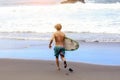 Back view of young fit surfer man with surfboard runs into ocean or sea with big waves for surfing. Concept of extreme Royalty Free Stock Photo