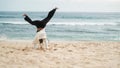 Back view a young girl with braids doing a handstand on the beach near the ocean Royalty Free Stock Photo