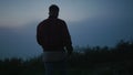 Back view young guy walking in field at morning. Casual man hiking in mountains Royalty Free Stock Photo