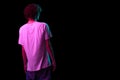 Back view of young hairy man, student in white tee isolated on dark background in neon light. Concept of emotions