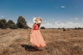 Back view of young happy woman in red summer dress and straw hat standing on yellow farm meadow Royalty Free Stock Photo