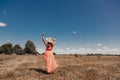 Back view of young happy woman in red summer dress and straw hat standing on yellow farm meadow Royalty Free Stock Photo