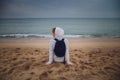 Back view of young lonely woman relaxing on beach in Barcelona,