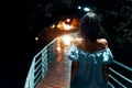 Young lonely woman walking on the bridge at night