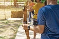 Back view of young man aims archery bow and arrow to colorful target in shooting range during training. Exercise and concentration