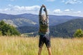 Back view of young man, standing in yellow summer field, exercising and stretching hands, looking at mountains Royalty Free Stock Photo