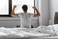 Back view of young man in pajamas stretching while sitting Royalty Free Stock Photo