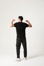 Back view of young man posing over white background wearing black clothing. Royalty Free Stock Photo