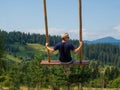 man traveler enjoying of swinging on heavenly swing and mountain view
