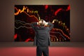 Back view of man standing in interior with falling red forex chart on screen. Finance and recession concept Royalty Free Stock Photo