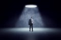 Back view of man standing in spotlight of lamp in concrete interior Royalty Free Stock Photo