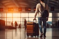 Back view of young man with suitcase in airport terminal. Travel and tourism concept, Close up of a man walking with luggage in Royalty Free Stock Photo