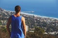 Back view of young man in a tank shirt looking at sea landscape from a mountain top Royalty Free Stock Photo