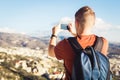 Back view of a young man tourist with backpack taking photo of landscape with smartphone Royalty Free Stock Photo