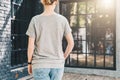 Back view. Young millennial woman dressed in gray t-shirt is stands on city street. Mock up. Royalty Free Stock Photo
