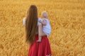 Back view of young mother with beautiful hair holding baby. Mother and child in wheat field Royalty Free Stock Photo