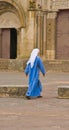 Back view of a young nun walking to door of a church