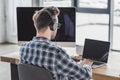 back view of young programmer in headphones and eyeglasses working Royalty Free Stock Photo