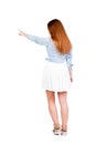 Back view of young redhead woman pointing at wall. beautiful gir Royalty Free Stock Photo