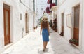 Back view of young tourist woman on ancient street in old town. Travel woman in straw hat and blue dress enjoying vacation in Royalty Free Stock Photo