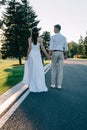 back view of young wedding couple holding hands and walking on walkway Royalty Free Stock Photo