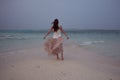 Back view of young woman against a sea horizon. Brunette girl in white skirt flying on wind. Royalty Free Stock Photo