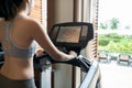 Back view of young woman athlete running on treadmill in gym