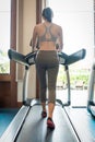 Back view of young woman athlete running on treadmill in gym