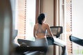 Back view of young woman athlete running on treadmill in gym