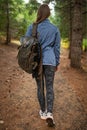 Back view of young woman with backpack walking in the forest. Enjoy the nature. Relax. Travel journal. Fantastic weekends