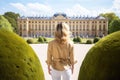 back view of young woman in beige jacket looking away at park, Female tourists standing in front of the Schonbrunn royal palace