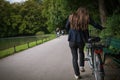 Back view of young woman with bicycle in the park on the background of trees Royalty Free Stock Photo