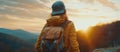 Back view of young woman in cap with backpack, sunset mountains outdoor travel concept