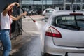 Back view of young woman cleaning her car on self service car. Female washing with jet sprayer. White foam on car Royalty Free Stock Photo