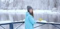 Back view of young woman with a cup of hot tea or coffee on snowy winter waterside. Royalty Free Stock Photo