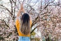 Back view of young woman enjoying beginning of spring against bloomy fruit tree with pink flowers in park Royalty Free Stock Photo