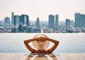 Back view of young woman in hat relaxing in swimming pool on the roof top of hotel and enjoy cityscape Royalty Free Stock Photo