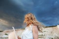 Back view of young woman with long flowing blond hair in the wind against the background of the sea and horizon. Beautiful girl Royalty Free Stock Photo